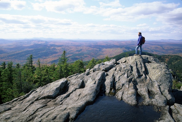 Hiker on top of Borestone Mtn. views the vastness of Maine Woods in autumn, Maine. (George Wuerthner)