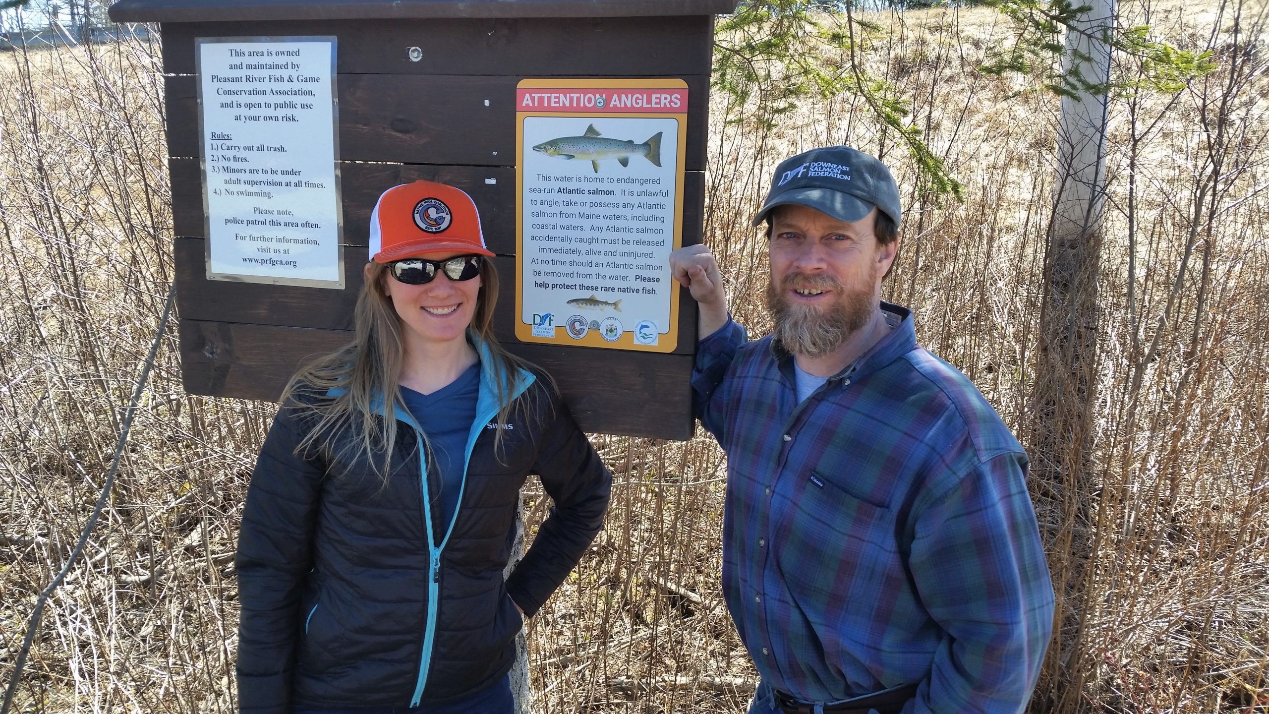 Emily Bastian, National Chair for Native Fish Coalition, and Dwayne Shaw, Executive Director for Downeast Salmon Federation posting an informational sign on the Pleasant River in Maine. (© Bob Mallard)